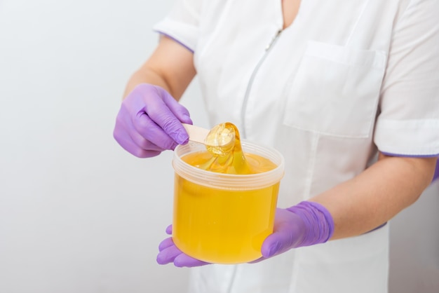 Natural honey sugar paste shugaring closeup women beautician holds jar wax of paste for sugar depila...