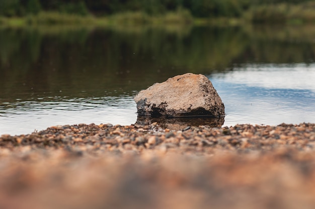 Paesaggio naturale del lago, alta definizione, il movimento delle onde sullo sfondo della foresta. il riflesso delle nuvole sulle increspature dell'acqua. in primo piano c'è una grande pietra