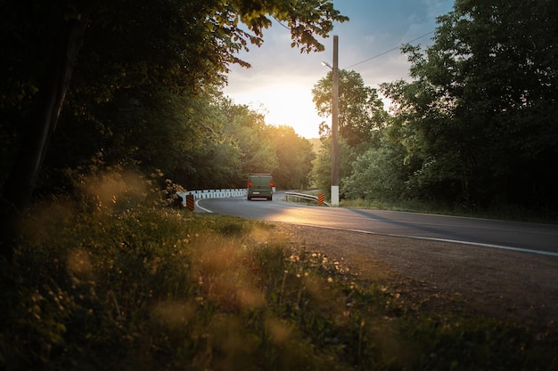 Natural landscape of road in forest on background of sunset