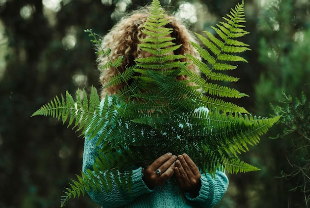 Фото Естественный образ жизни и любовь к природе люди концепция здорового образа жизни зеленые листья и женщина за лесом на заднем плане здоровый досуг на свежем воздухе окружающая среда и празднование дня земли