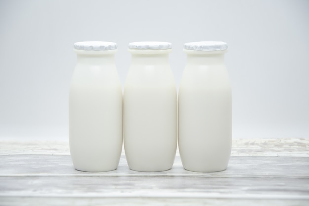 Natural liquid yogurt with probiotics in small plastic bottles on wooden table.