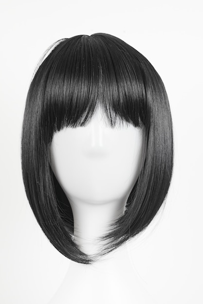 Natural looking black wig on white mannequin head Medium length straight hair with bangs on the metal wig holder isolated on white background front view