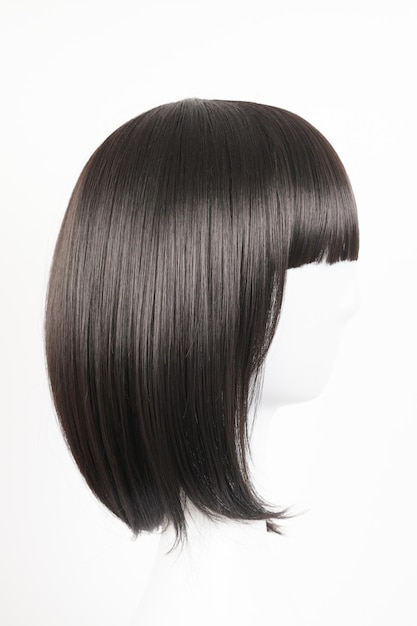 Natural looking black wig on white mannequin head Medium length straight hair with bangs on the metal wig holder isolated on white background side view