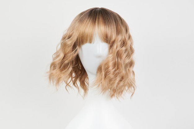 Natural looking blonde fair wig on white mannequin head Middle length hair cut on the plastic wig holder isolated on white background front view