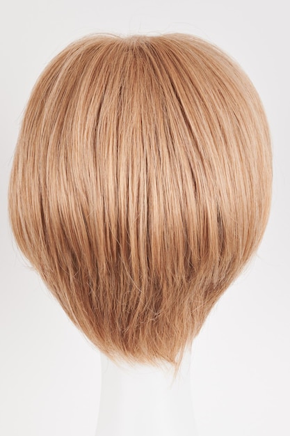 Natural looking blonde fair wig on white mannequin head Short hair cut on the plastic wig holder isolated on white background back view