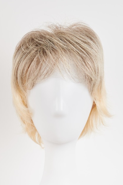 Natural looking blonde fair wig on white mannequin head Short hair cut on the plastic wig holder isolated on white background front view