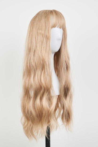 Natural looking blonde wig on white mannequin head Long hair on the plastic wig holder isolated on white background