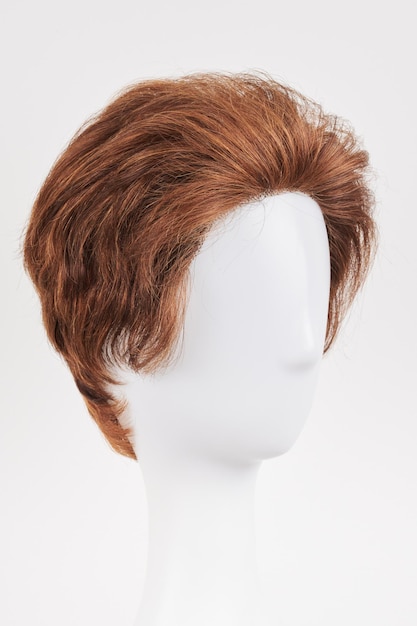 Natural looking dark brunet wig on white mannequin head Short brown hair on the plastic wig holder isolated on white background side view