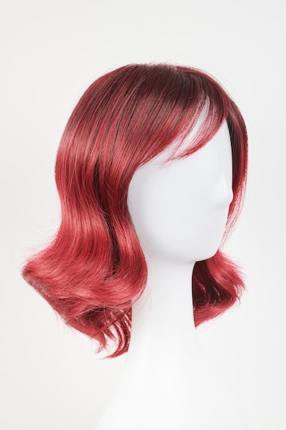 Natural looking red wig on white mannequin head Medium length hair on the plastic wig holder isolated on white background side view