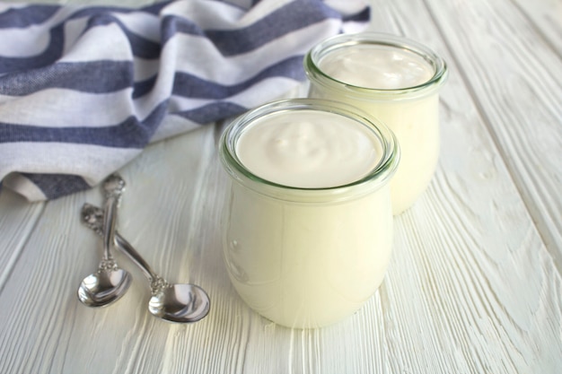 Natural milk yogurt in the glass jars on the white wooden