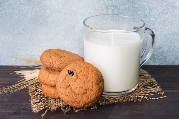 Natural oatmeal cookies and a glass of milk on a wooden background