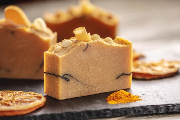 Natural orange soap on the black and wooden background Concept of making and using organic eco soap and cosmetics