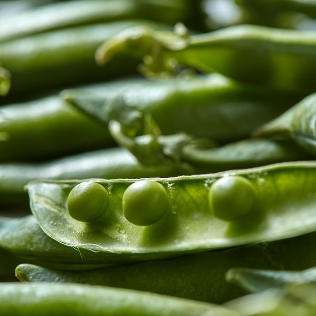 ソフトフォーカスのエンドウ豆とインゲンの鞘を持つ自然な有機的な背景。新鮮な菜食主義のデトックスを食べることの概念。