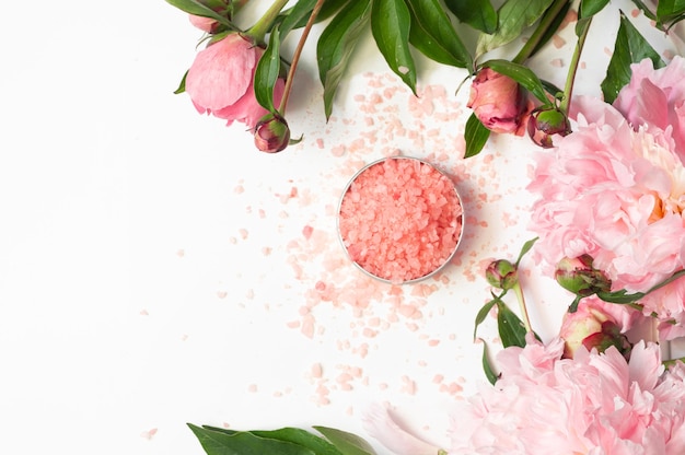 Natural organic cosmetic products with pink peonies flowers on white background. Spa relax Treatments and anti-cellulite massage. Beauty, nature cosmetics for bath spa, skin care, flat lay.