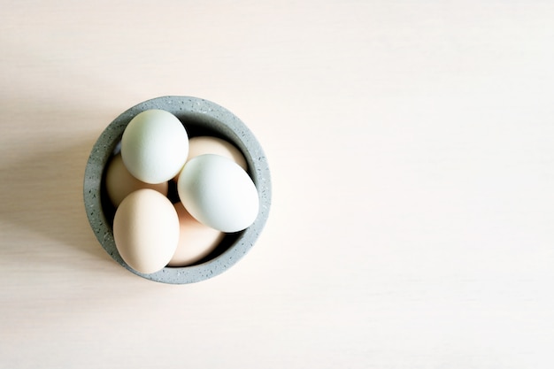 Natural organic Easter eggs and feathers in ceramic bowl on white background