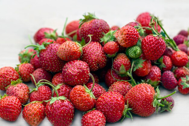 Natural organic food production. Freshly picked juicy strawberries on wooden background. Heap of summer red berries. Homegrown, gardening and agriculture consept. Backlight