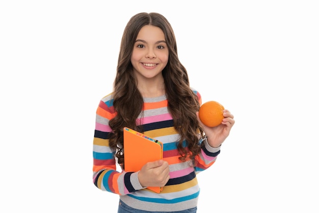 Natural organic fresh citrus fruit back to school knowledge happy kid girl with orange and school notebook vitamin and dieting child with lunch healthy childhood