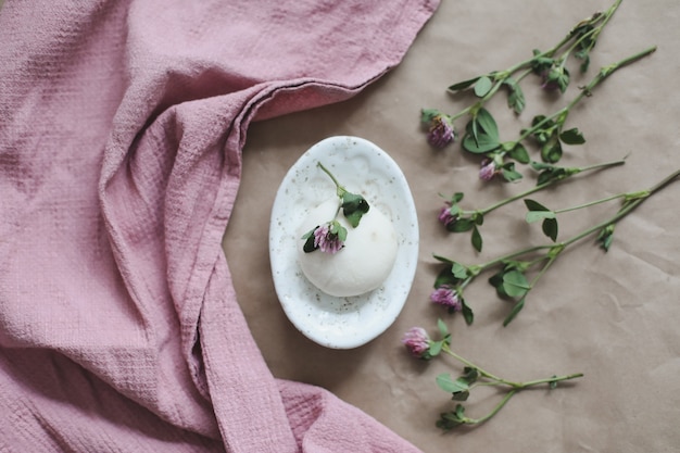 Natural organic soap with flowers and pink towel on craft paper background top view with copyspace