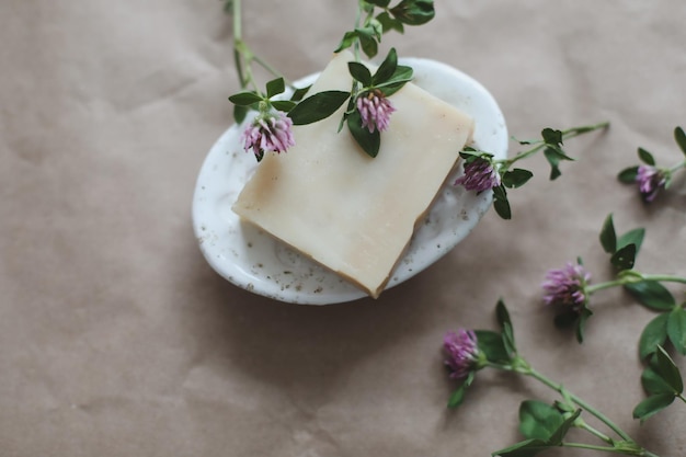 Sapone organico naturale con fiori e asciugamano rosa su sfondo di carta artigianale vista dall'alto con copyspace