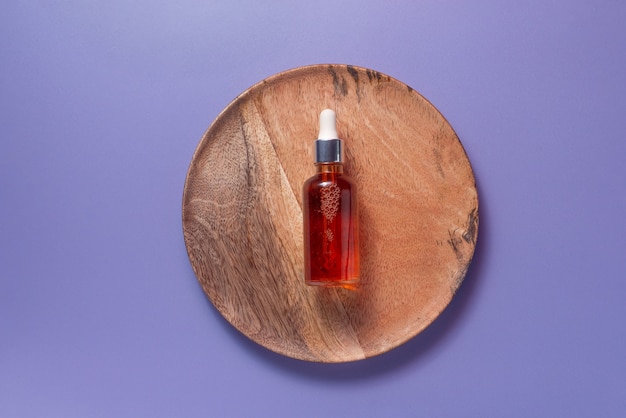 Natural organic vitamin c serum on a wooden plate on violet background