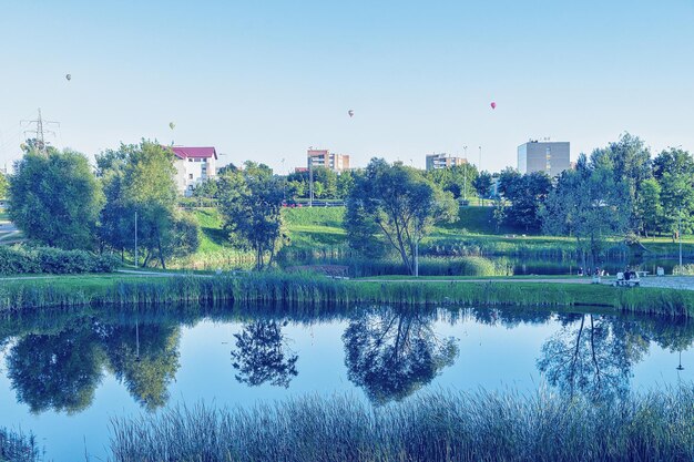 市内に池のある自然公園。背景に熱気球。ビリニュス。トーン