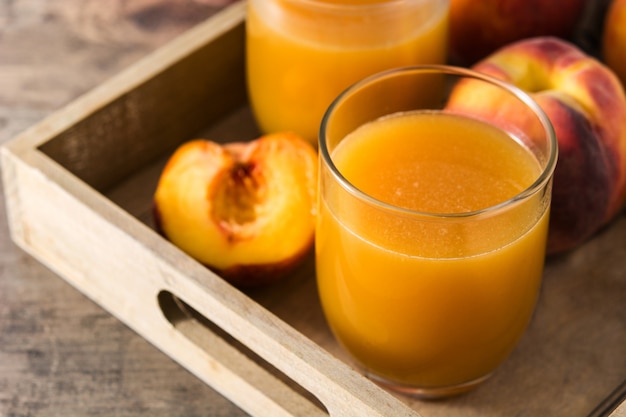 Натуральный персиковый сок в стакан на деревянный стол