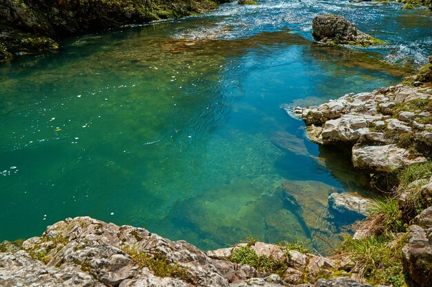 The natural pool of the mountain river with emerald clear water