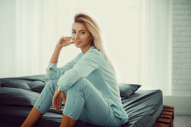 Natural pretty blonde sitting on bed