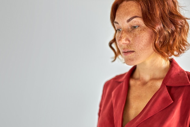 natural red haired woman looking away in contemplation, posing at camera, people concept