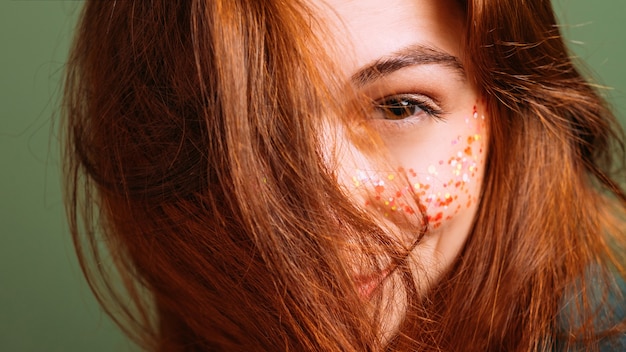 Natural redhead beauty. People diversity. Young woman portrait. Curious look. Glitter freckles makeup.