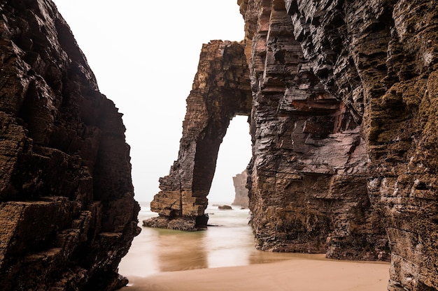 Natural rock arches on Cathedrals beach in low tide Spain