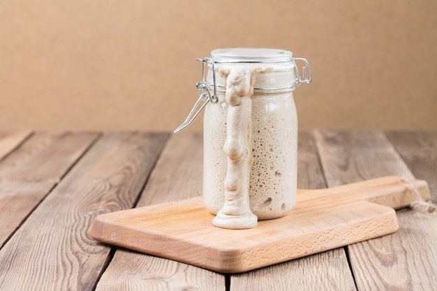 Photo natural rye sourdough in a closed jar on the table ran out. the fermentation process.