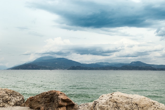 イタリアのガルダ湖の自然の風景。非常に美しい風景、青緑色の水できれいな淡水湖、地平線上の山、空の雲。