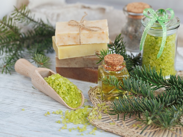 Natural sea salt and handmade soap with branch of pine on white wooden.