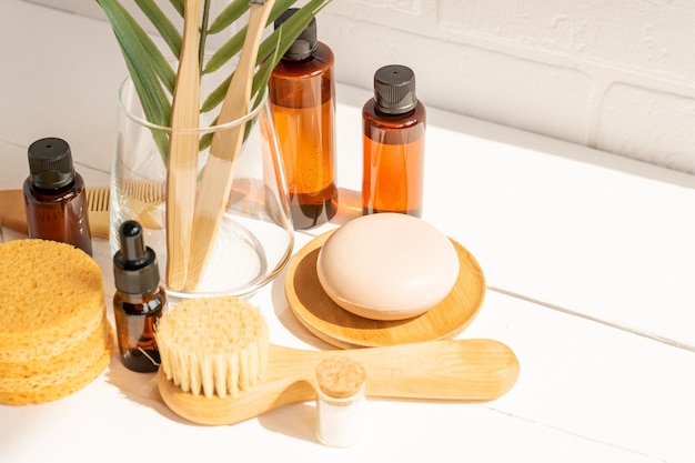 Natural serum, dry soap, sponges and face massaging brush with natural bristle on a table. Presentation of organic eco friendly spa beauty products in neutral colors nature environment.