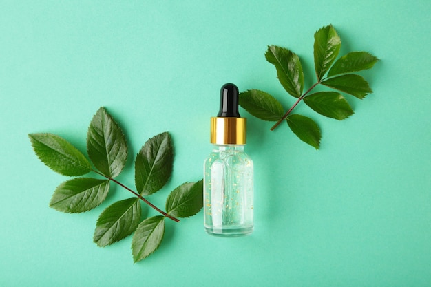 Natural skincare bottle container and organic green leaf , flowers ingredients with the laboratory glassware on mint surface