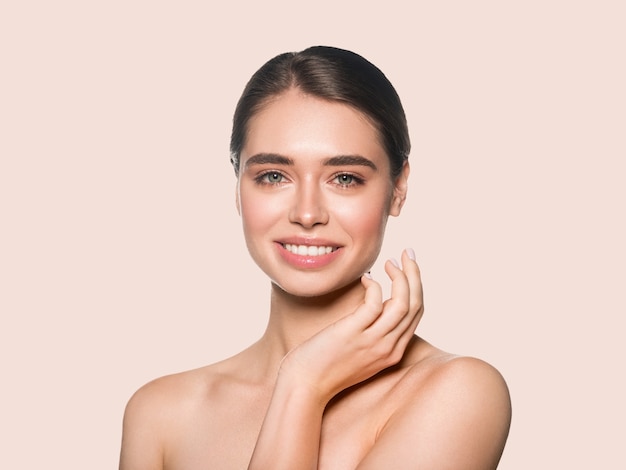 Natural smiling brunette make up woman beauty cosmetic touching her face. Color background. Pink