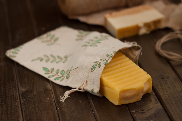 Photo natural soap in a linen back on brown wooden table