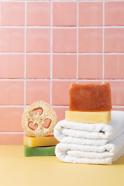 Natural soap and loofah sponge cotton towels eco friendly body care on table inside a bathroom wall tiles ceramic background