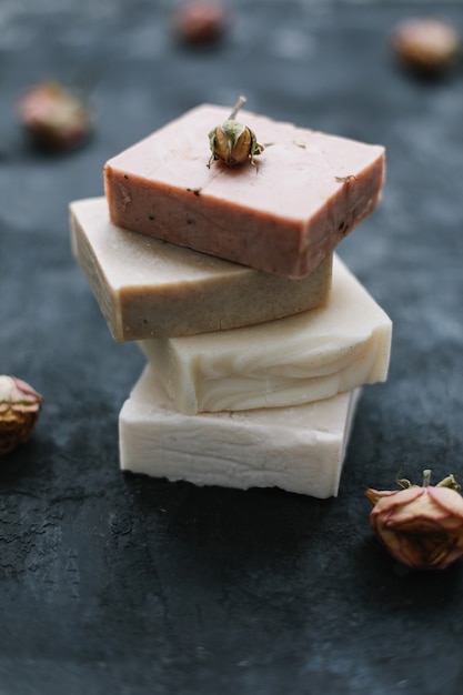 Natural soap and rose flowers on dark surface