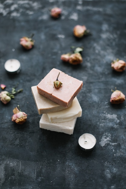 Natural soap and rose flowers on dark surface