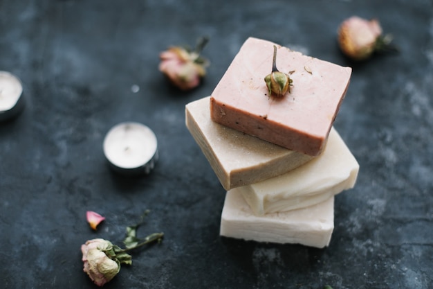 Sapone naturale e fiori di rosa su superficie scura