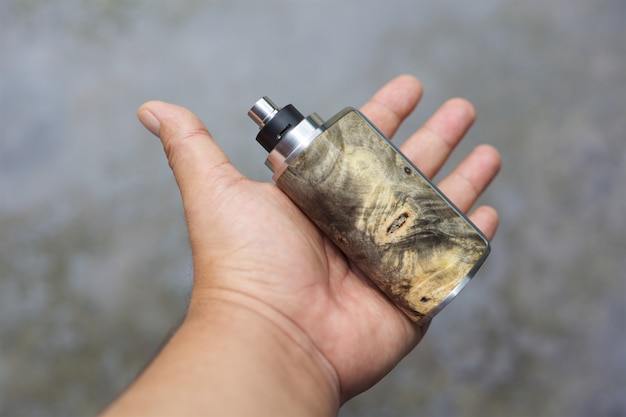 natural stabilized wood box mods with rebuildable dripping atomizer and beauty ring in hand, vaporizer