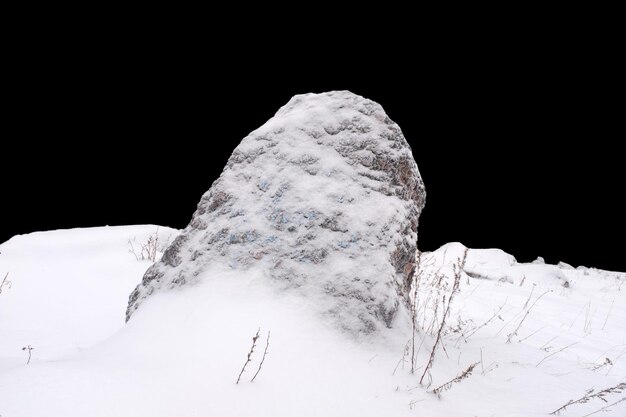 Натуральный камень в снегу на черном фоне Фото высокого качества