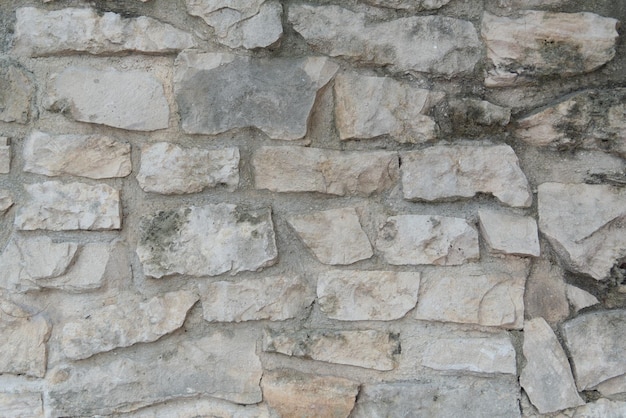 Natural stone wall Gray stone background A wall of stones of various sizes filled with cement