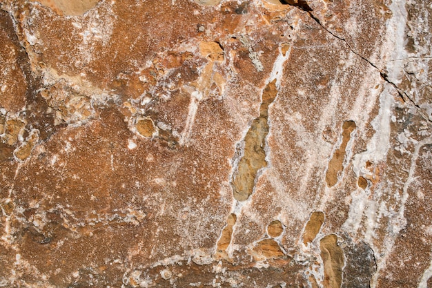 Natural stony grunge rufous background with crack and white spots.