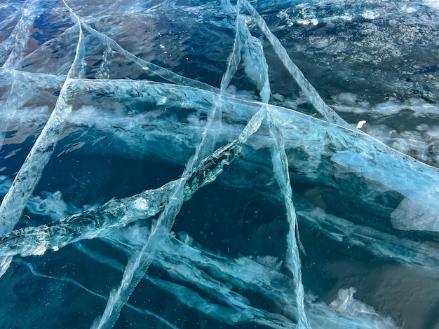 The natural texture of winter ice with white bubbles and cracks on a frozen lake Abstract background of ice and cracks on the surface of frozen Lake Baikal