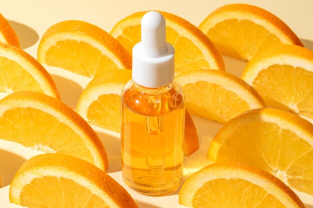 Фото Естественная сыворотка витамина с эфирные масла для ухода за кожей бутылка сыворотки витамина с со свежими сочными апельсиновыми фруктами мокет брендинга косметических продуктов