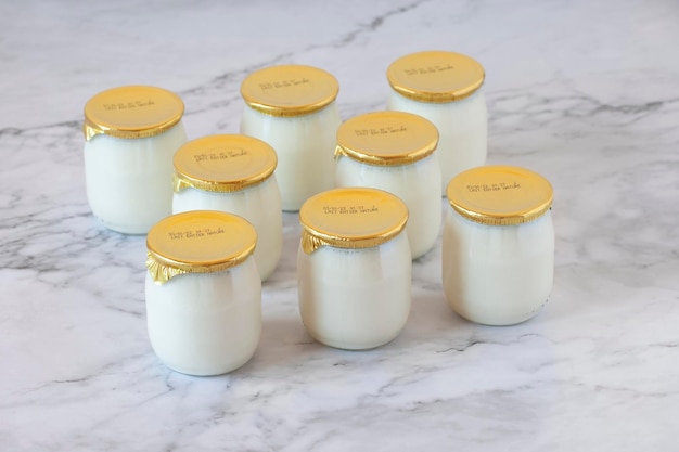 Natural whole milk industrial yogurt in glass pots with the\
expiration date