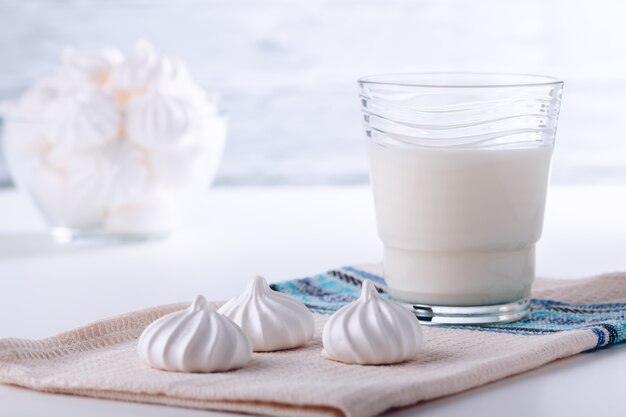 Natural whole milk in a jug and glass with bizet on the background of a white brick wall